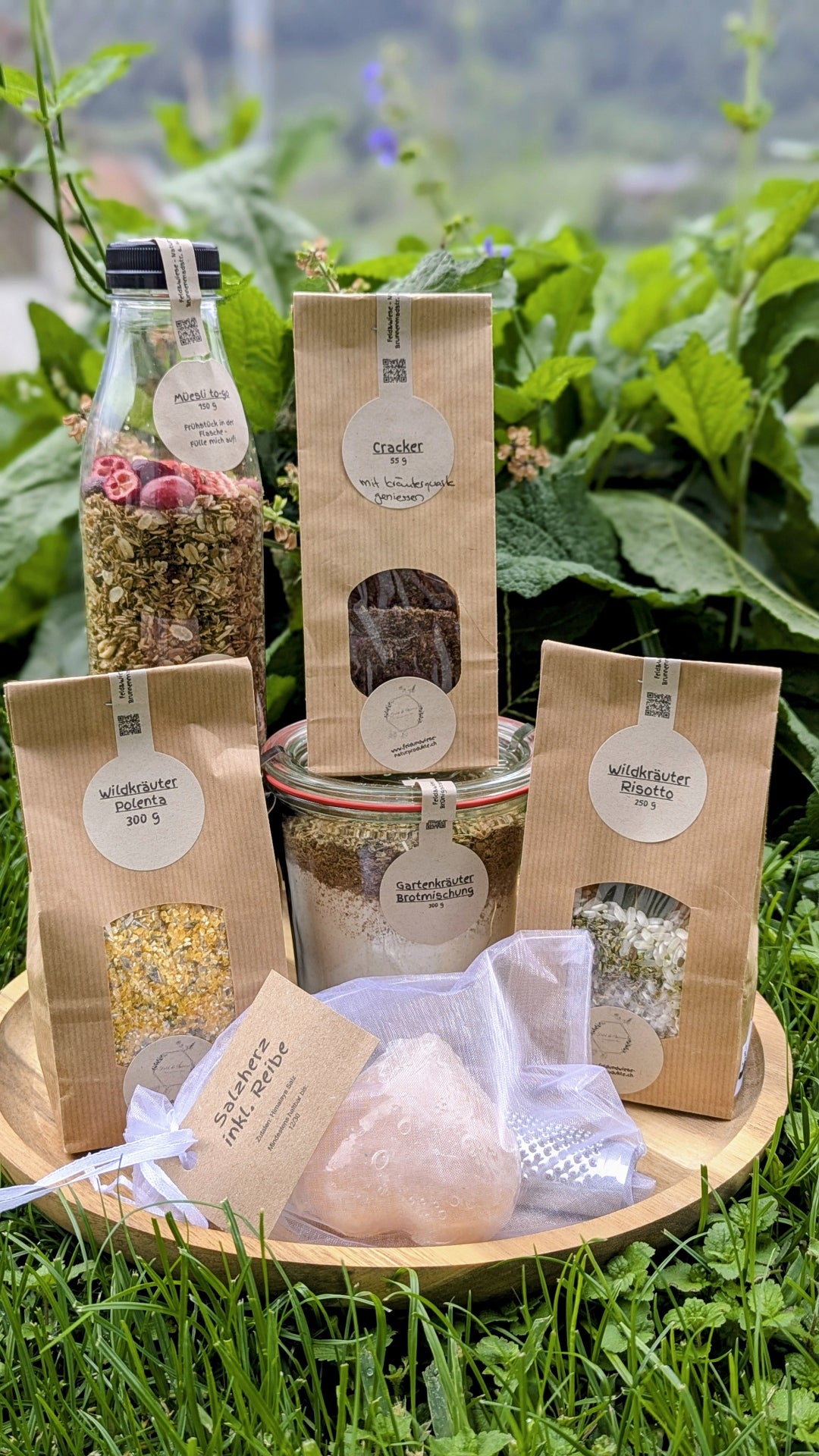 Feld & Wiese Degustationsbox mit 6 Naturprodukten aus der Zentralschweiz auf Holzteller im Grünen