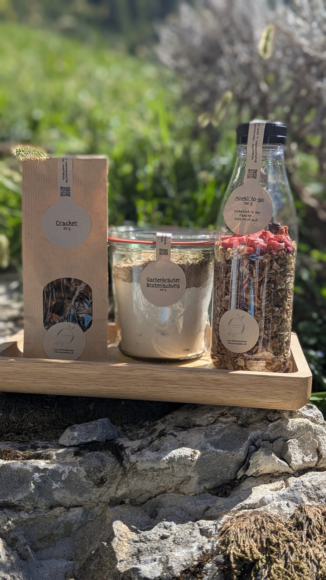 Feld & Wiese Frühstückskorb mit Müesli, Brotmischung und Crackern auf Holztablett in der Natur