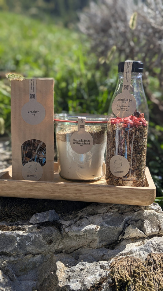 Feld & Wiese Frühstückskorb mit Müesli, Brotmischung und Crackern auf Holztablett in der Natur